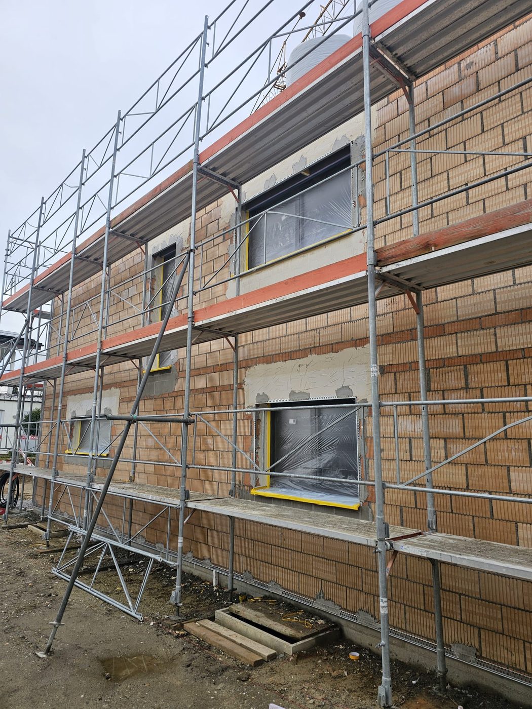 Backstein-Rohbau mit abgeklebten Fensteröffnungen vor dem Verputzen